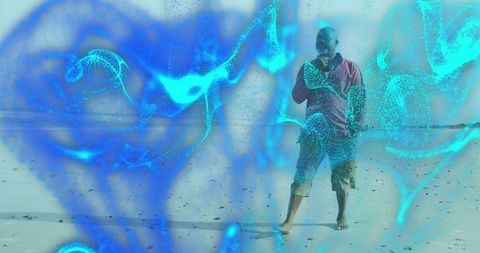 Senior Man Walking on Beach with Digital Cyan Particles Overlay