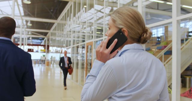 Businesswoman Talking on Smartphone Walking Through Modern Office - Download Free Stock Images Pikwizard.com