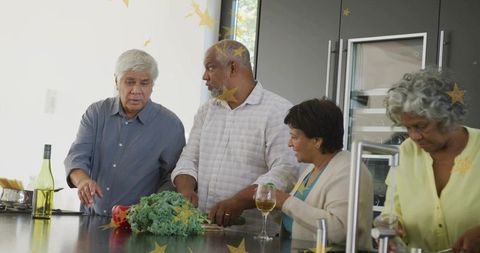 Multigenerational friends preparing dinner together at modern kitchen island with wine