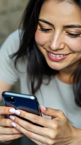 Vertical smartphone video: Woman smiling while scrolling phone during relaxed home moment