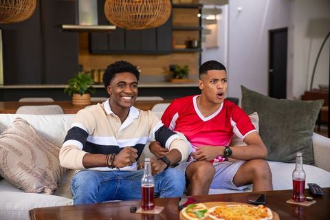 Two Friends Watching Sports at Home and Enjoying Pizza