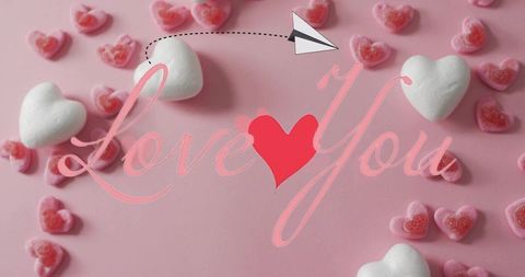Romantic valentine flatlay with marshmallow hearts pink gummy candies cursive love you