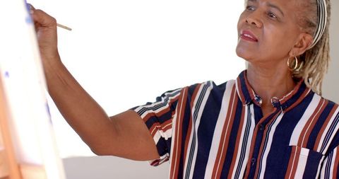 Senior african american woman painting in sunlit room