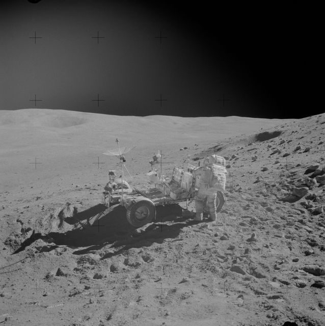 AS16-110-17960 (22 April 1972) --- Astronaut John W. Young, commander, replaces tools in the Apollo Lunar Hand Tool (ALHT) carrier at the aft end of the Lunar Roving Vehicle (LRV) during the second Apollo 16 extravehicular activity (EVA) on the high side of Stone Mountain at the Descartes landing site. Astronaut Charles M. Duke Jr., lunar module pilot, took this photograph near the conclusion of Station 4 activities. Smoky Mountain, with the large Ravine Crater on its flank, is in the left background. This view is looking northeast. While astronauts Young and Duke descended in the Apollo 16 Lunar Module (LM) "Orion" to explore the Descartes highlands landing site on the moon, astronaut Thomas K. Mattingly II, command module pilot, remained with the Command and Service Modules (CSM) "Casper" in lunar orbit.