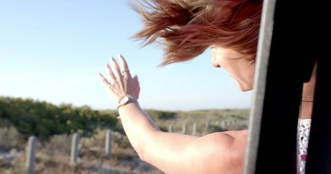 Carefree Young Woman Enjoying Road Trip Adventure, Embracing Fresh Air