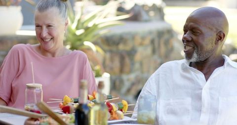 Smiling Couple Dining Together on Sunny Patio with Skewers