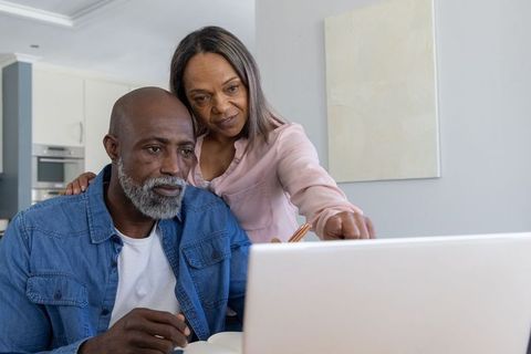 Mature couple collaborating on laptop in kitchen workspace for budgeting and planning