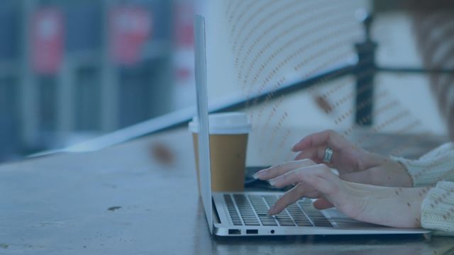 Woman using laptop in contemporary workspace with coffee cup on table. Great for illustrating themes of productivity, business, technology use, and modern office settings. Ideal for blogs, websites, or advertisements focusing on professional activities and remote work.