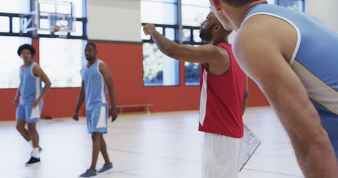 Basketball Coach Advancing Strategy with Team on Indoor Court