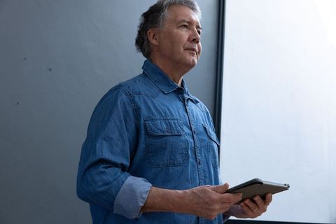 Mature Professional Contemplating in Modern Office with Tablet