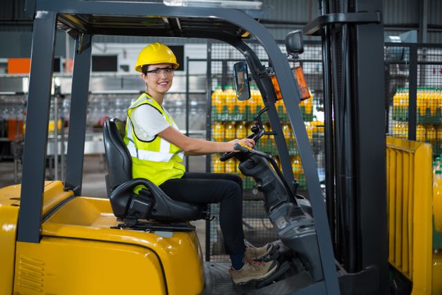 Portrait of smiling female factory worker driving forklift in factory