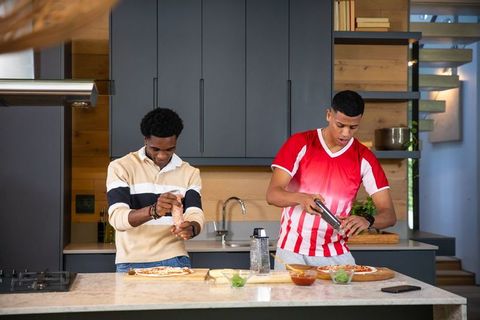Diverse friends preparing homemade pizza together in modern kitchen