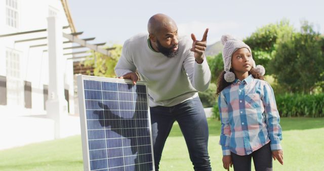 Father and daughter outdoors learning about solar energy. They are engaging in sustainability education, promoting renewable resources, and family bonding. Ideal for use in content related to education, renewable energy, sustainability, environmental conservation, and parenting.