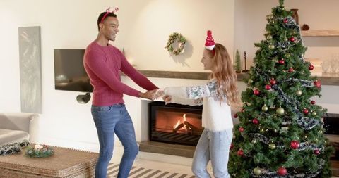 Joyful Couple Dancing at Home Near Christmas Tree and Fireplace