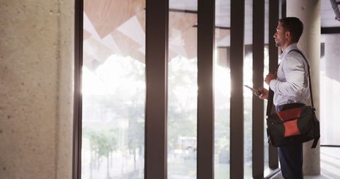 Businessman Standing in Modern Office Lobby with Smartphone