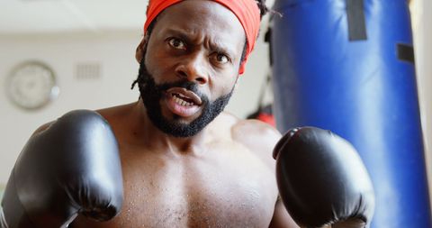 Male Boxer in Aggressive Mood Training in Fitness Gym