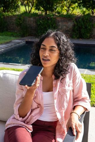 Woman enjoying relaxation outdoors speaking into smartphone