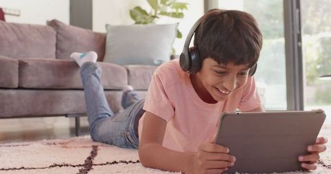Boy enjoying tablet entertainment with headphones in comfortable living room