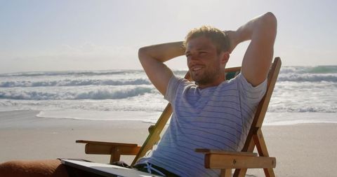 Young Man Relaxing on Beach with Sun Lounger