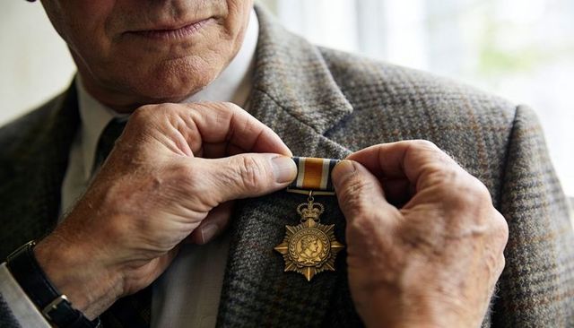 Senior veteran receiving medal on tweed jacket at formal ceremony