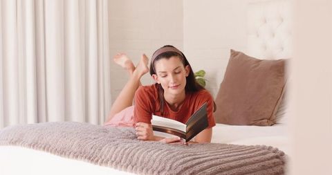 Woman relaxing on bed with book in cozy atmosphere
