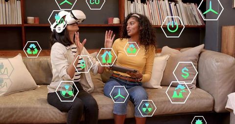Women Exploring Augmented Reality Energy Icons Using VR Headset and Tablet on Couch