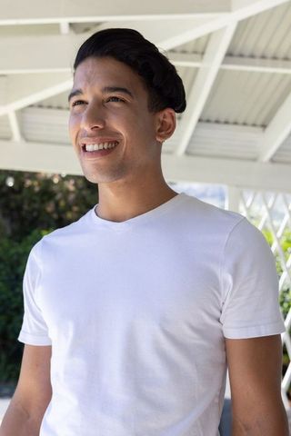 African american man smiling on sunlit patio wearing white crew-neck t-shirt