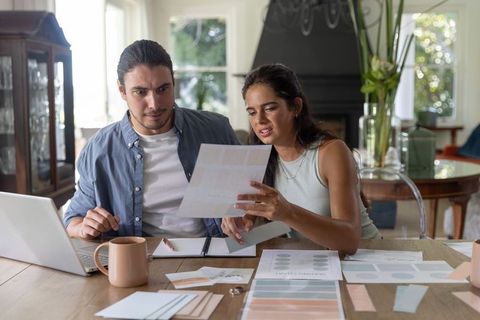 Young couple reviewing household documents and color swatches for home renovation planning
