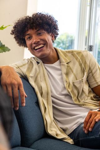 Smiling young man relaxing on navy couch in sunlit modern living room