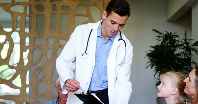 Male doctor is interacting with a young girl in a clinic waiting room. Doctor is holding a clipboard, smiling, and engaging with the child and her family, fostering a friendly and reassuring atmosphere. Suitable for healthcare promotional materials, pediatric care information, and clinic brochures.