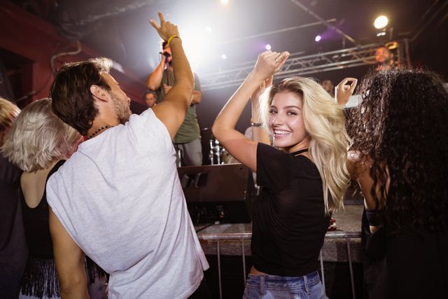 Portrait of smiling young woman with friends enjoying music concert at nightclub