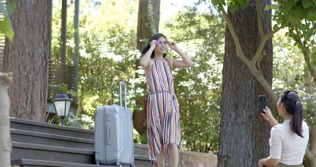 Two women enjoying summer vacation taking photos in park with suitcase - Download Free Stock Images Pikwizard.com