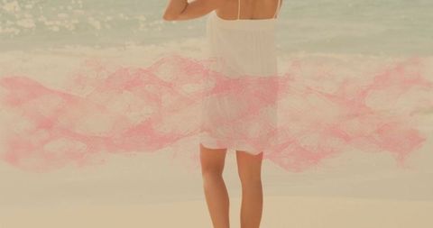 Woman adjusting sundress straps at tranquil beachside