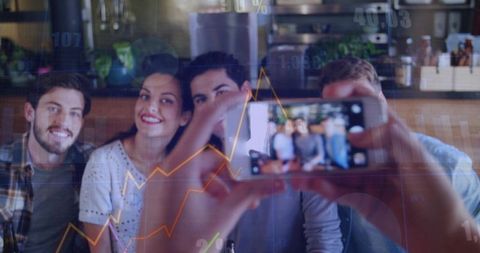 Young friends taking selfie in cozy cafe with smartphone and stock market graph overlays