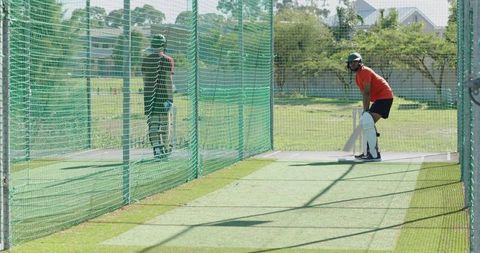 Cricket net practice: batsman preparing while bowler delivering fast pace ball outdoor