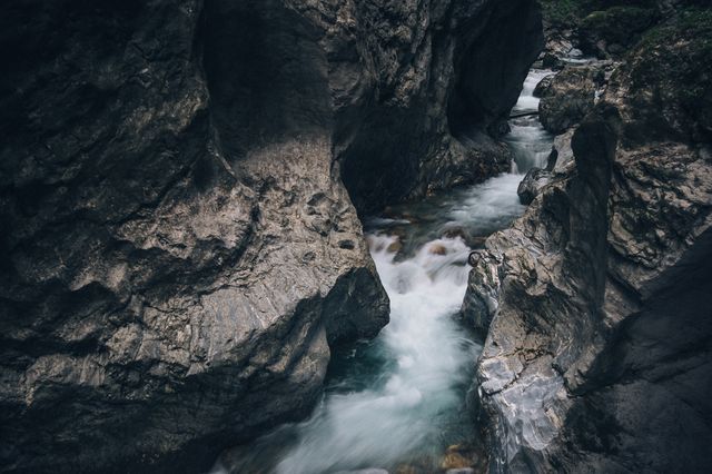 Deep rocky gorge with flowing stream offers stunning and tranquil natural scenery. Ideal for nature enthusiasts, hiking promotions, outdoor adventure marketing, geological study visuals, and landscape-focused content.