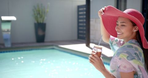Woman Relaxing by Pool with Refreshing Drink on Sunny Day