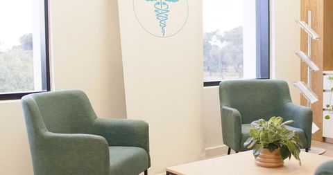 Calm clinic waiting area with green armchairs and indoor plant