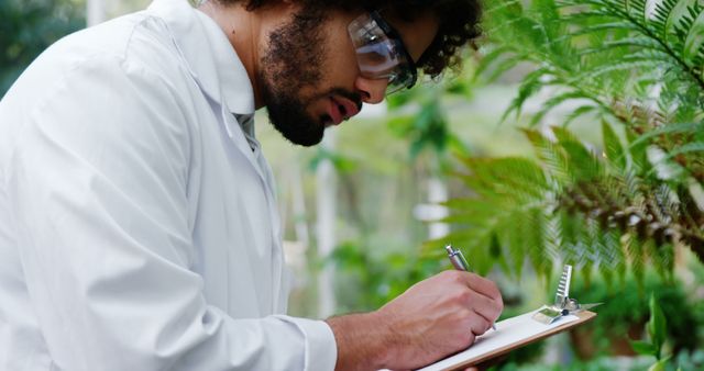 Botanist Recording Data Examining Plants in Greenhouse - Download Free Stock Images Pikwizard.com