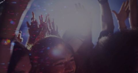 Smiling Indian Man Raising Hands Cheering in Crowded Neon Concert with Backlight Haze