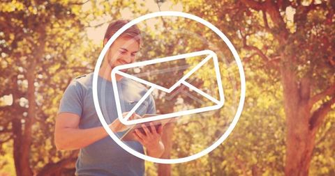 Smiling man checking tablet in sunlit park with email notification overlay
