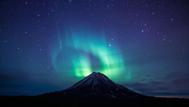 Northern Lights Dancing Over Snow-Capped Conical Mountain Under Starry Night Sky
