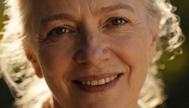 Smiling senior woman with backlit hair halo closeup portrait in golden garden light