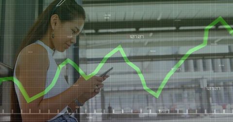Asian commuter checking smartphone with green analytics chart overlay at station
