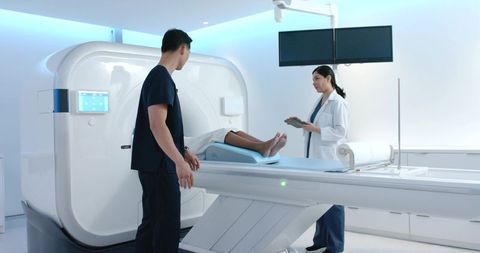 Medical team preparing patient for mri scan in modern radiology suite with digital tablet