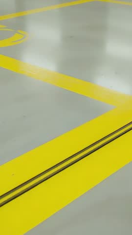 Vertical panning revealing industrial yellow floor markings and metal rails on epoxy