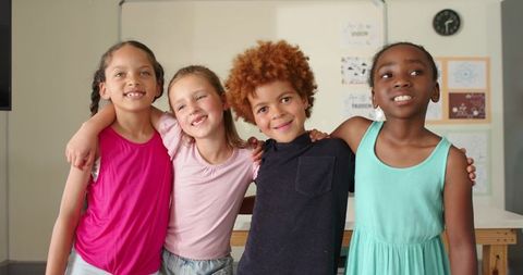 Preteen friends linking arms in classroom celebrating diversity, teamwork and joy