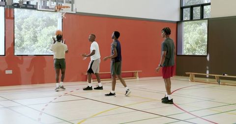 High school basketball team practicing driving, shooting and rebounding in school gym