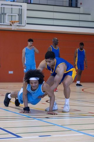 Male basketball players tumbling during intense game on indoor court
