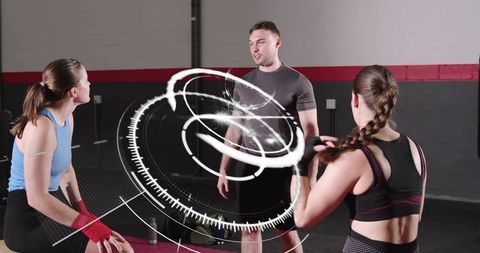 Male coach guiding two women during group fitness training with futuristic hud overlay
